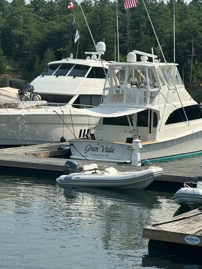 Gran Vida Yacht Photos Pics 1998 Ocean Yachts Super Sport docked with inflatable boat, flags, and lush greenery in background.
