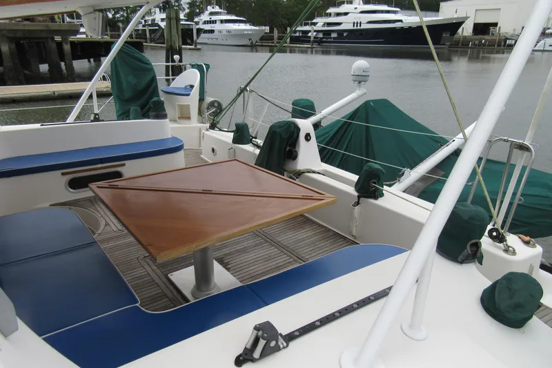 Pippin Yacht Photos Pics Catana 471 catamaran cockpit with wooden table, blue seating, docked near luxury yachts.
