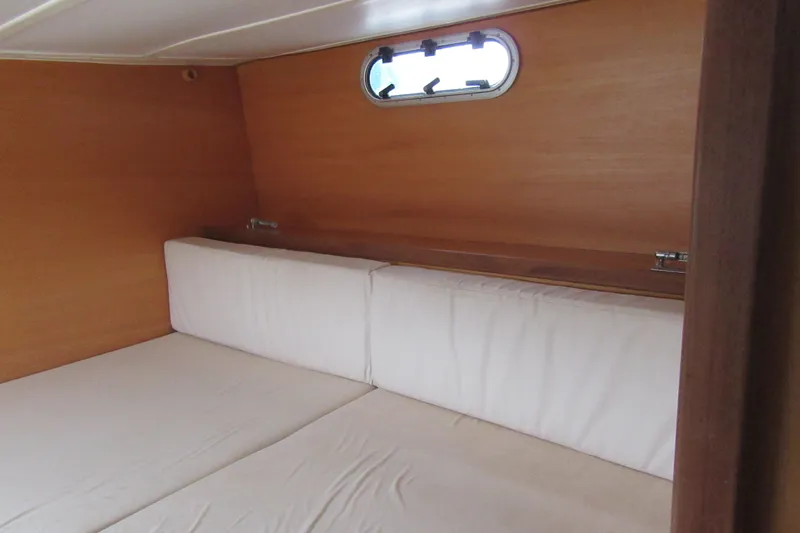 Pippin Yacht Photos Pics Interior cabin of 2001 Catana 471 yacht with wooden walls and white cushions.