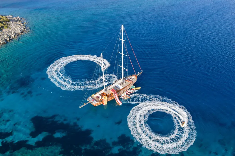 Take It Easier Yacht Photos Pics Aerial view of 2007 Custom Gulet Motorsailer with jet ski circles in clear blue water.