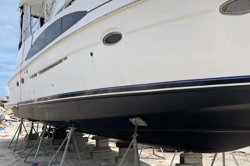 Sudden Comfort Yacht Photos Pics 2001 Carver 444 Cockpit Motor Yacht on stands, undergoing maintenance on a sandy shore.