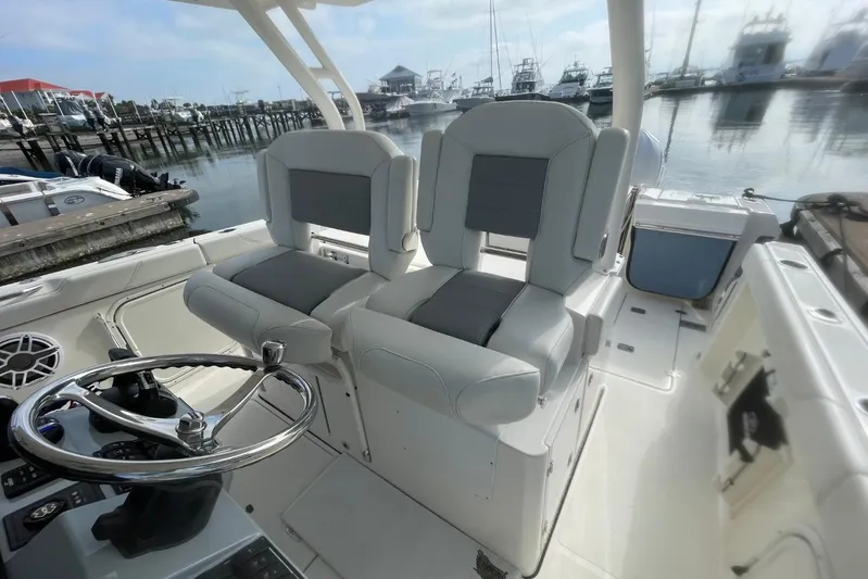 Equanimity Yacht Photos Pics 2021 Pursuit S 328 Sport boat interior with dual seats and steering wheel at marina.