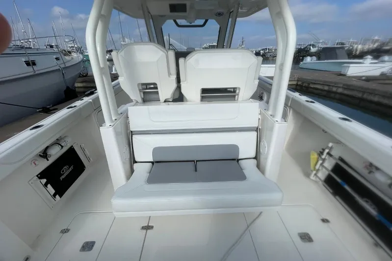Equanimity Yacht Photos Pics 2021 Pursuit S 328 Sport boat interior with seating and docked yachts in background.