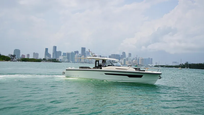 In-stock 2024 Nimbus T11 #258 Yacht Photos Pics Nimbus Tender 11 #258 (2024) cruising near a city skyline on a sunny day.