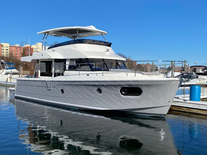  Yacht Photos Pics 2024 Beneteau Swift Trawler 48 docked in a marina on a sunny day.