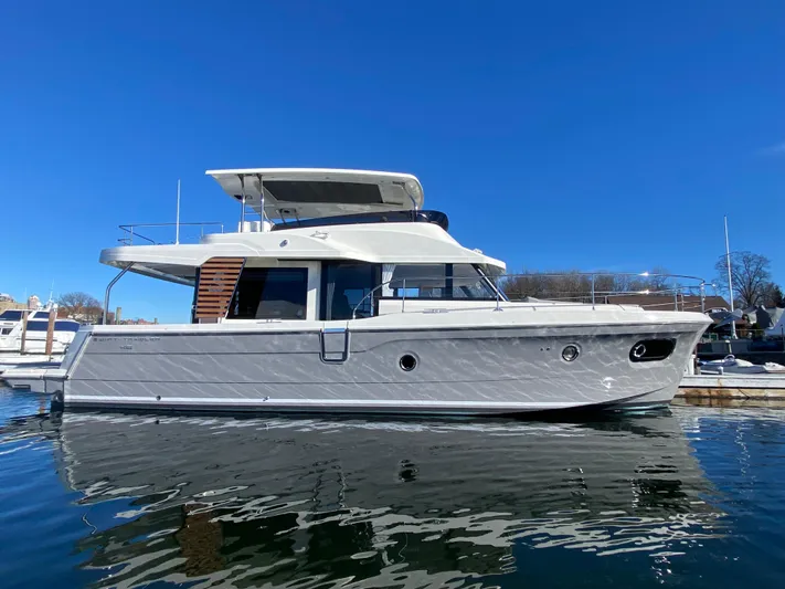  Yacht Photos Pics 2024 Beneteau Swift Trawler 48 on calm water under clear blue sky.