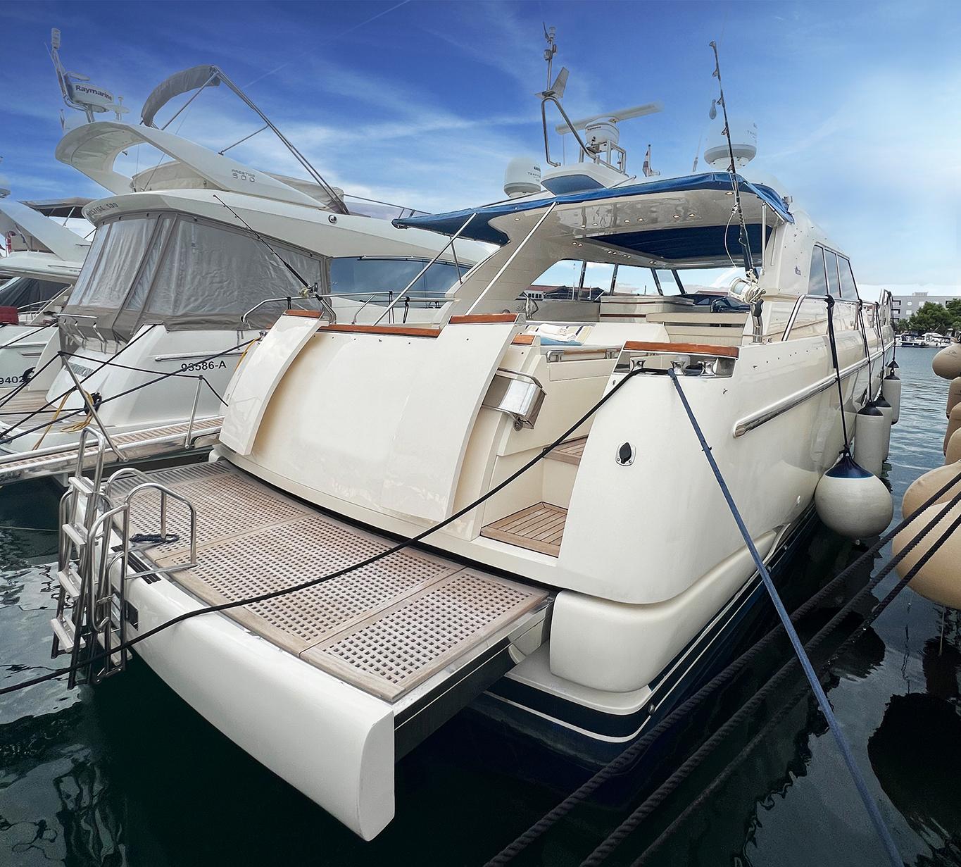 Luxury yacht Ilver Vista 58, 2002 model, docked at marina under clear blue sky.