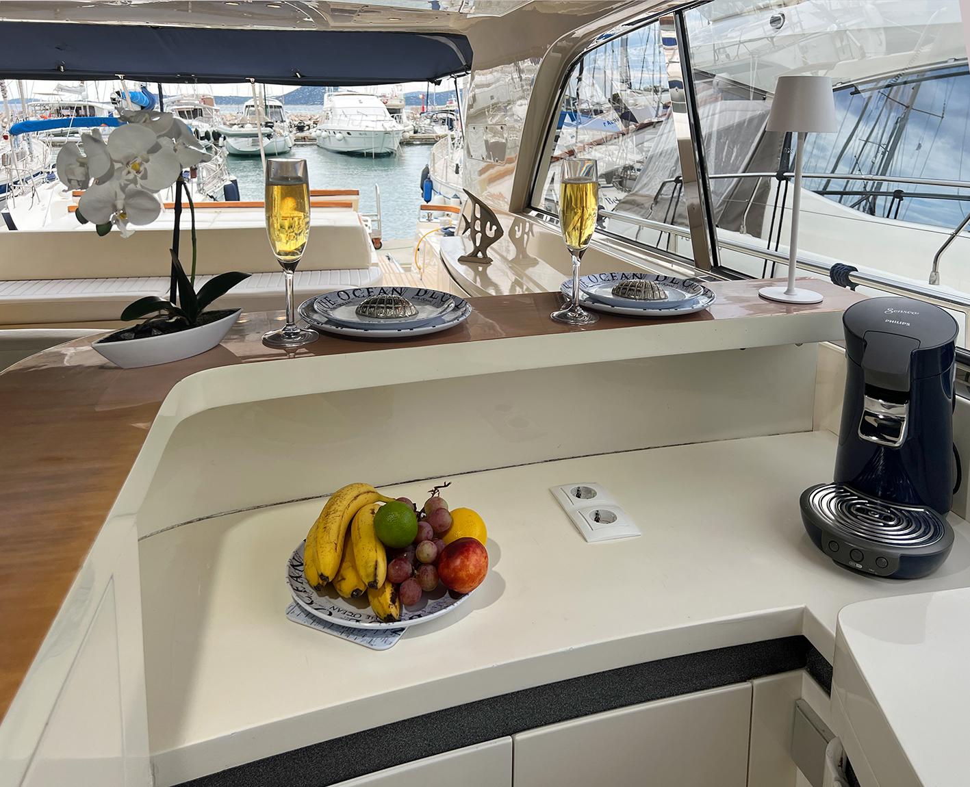Luxurious Ilver Vista 58 yacht interior with fruit, champagne, and elegant dining setup.