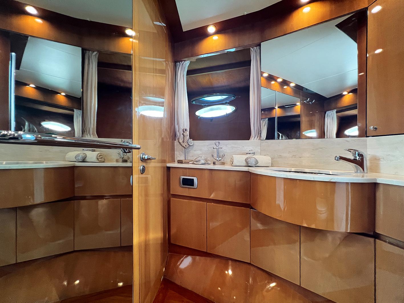 Luxurious bathroom interior of 2002 Ilver Vista 58 yacht with wooden cabinetry and mirrors.