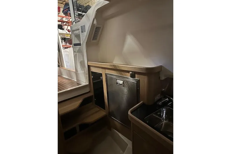  Yacht Photos Pics 2023 Nimbus C11 boat interior with wooden cabinetry and stainless steel appliances.