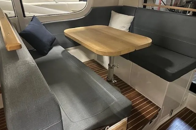  Yacht Photos Pics Cozy seating area in 2023 Nimbus C11 boat with wooden table and cushions.