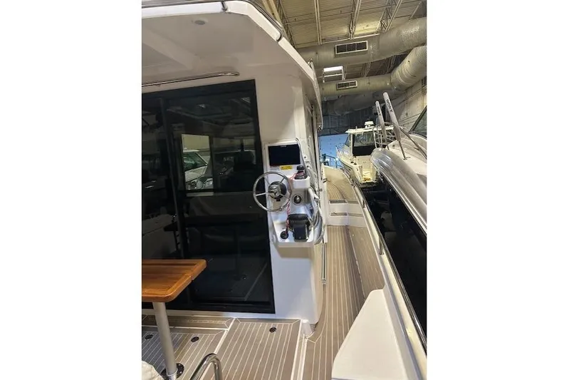  Yacht Photos Pics 2023 Nimbus C11 boat interior with steering console and wooden table in a showroom.