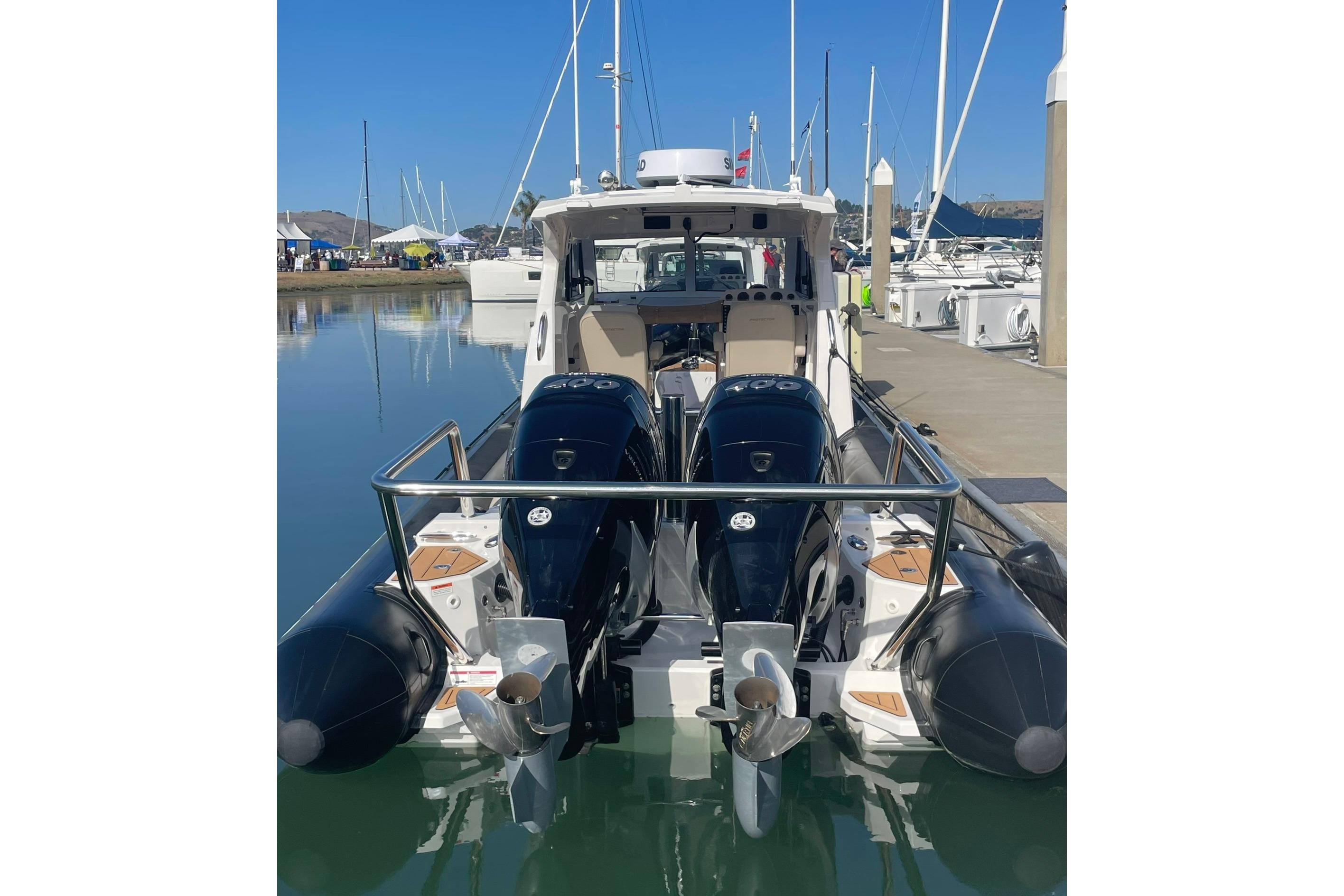 2024 Protector 330 Targa boat with twin 400 HP engines docked at marina.