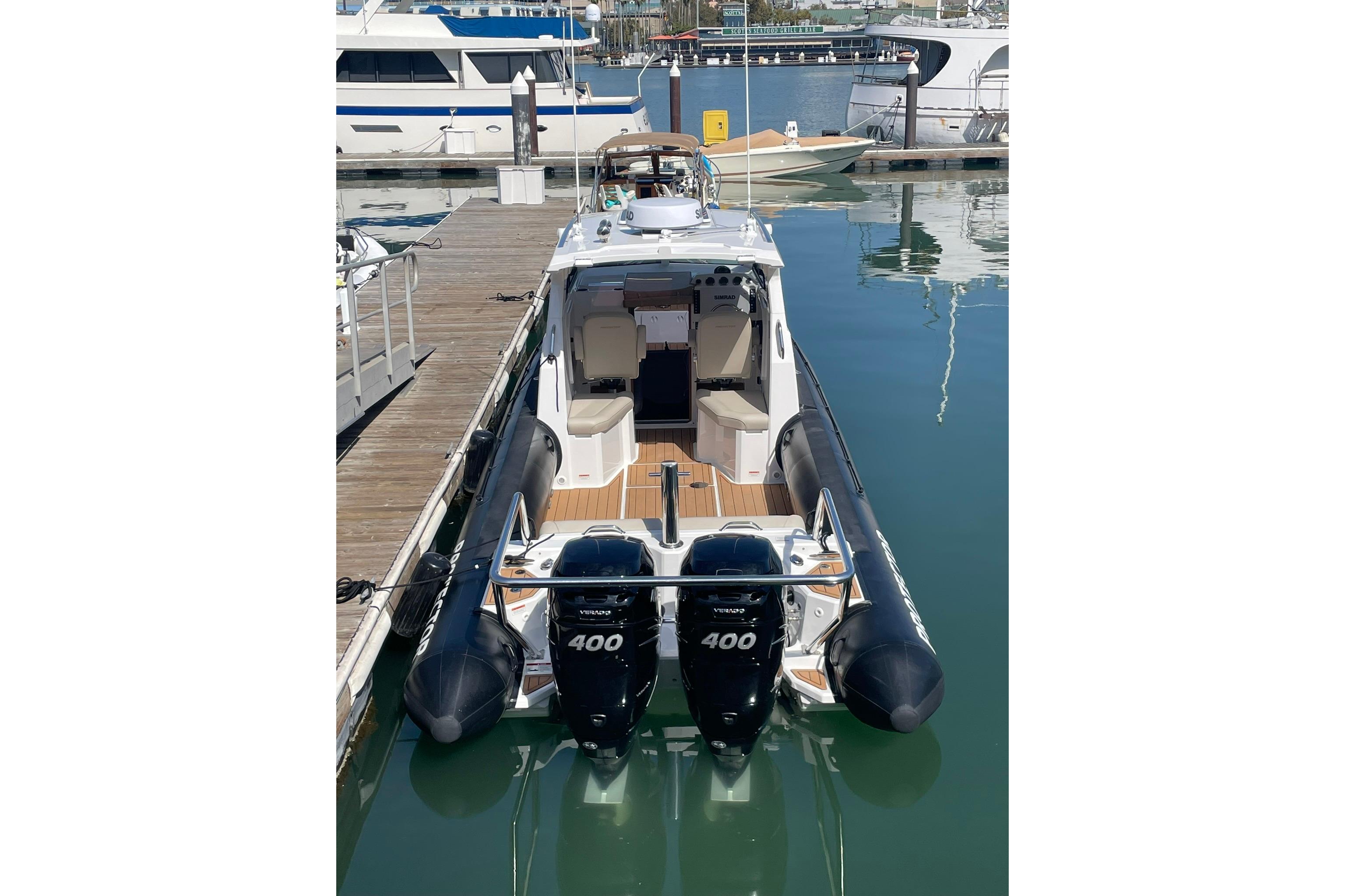 2024 Protector 330 Targa boat with twin 400 HP engines docked at marina.
