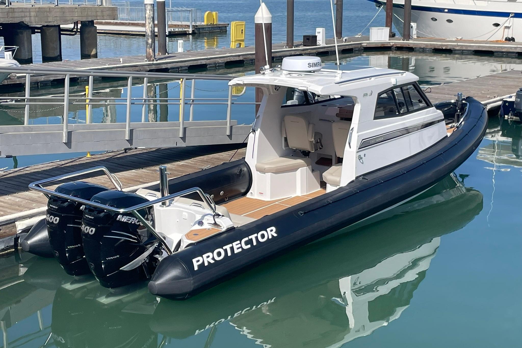 2024 Protector 330 Targa boat with twin 400 HP engines docked at marina.