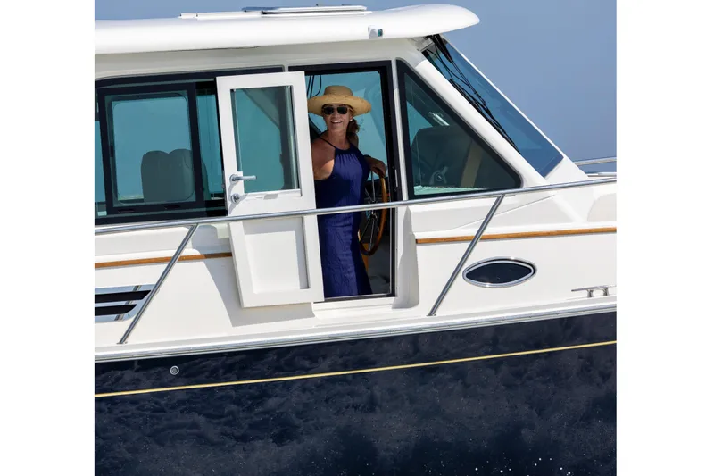 Ready For Customization Yacht Photos Pics Woman steering 2027 Back Cove 412 yacht, wearing a sun hat and sunglasses.