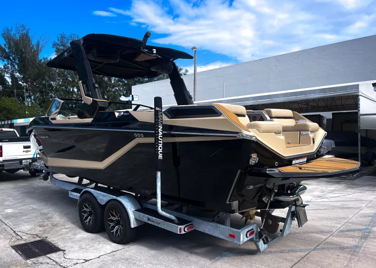 Yacht Photos Pics 2026 Nautique Paragon G25 boat on trailer, sleek design, parked outdoors under blue sky.