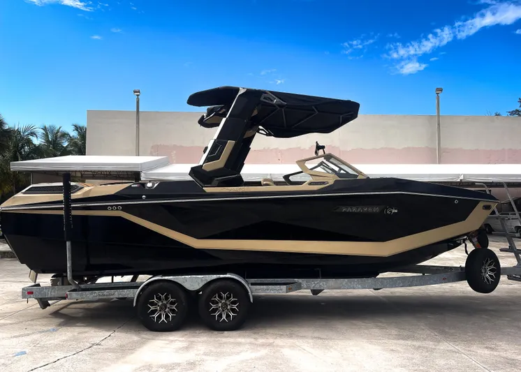  Yacht Photos Pics 2026 Nautique Paragon G25 boat on trailer, sleek design, black and beige color scheme.