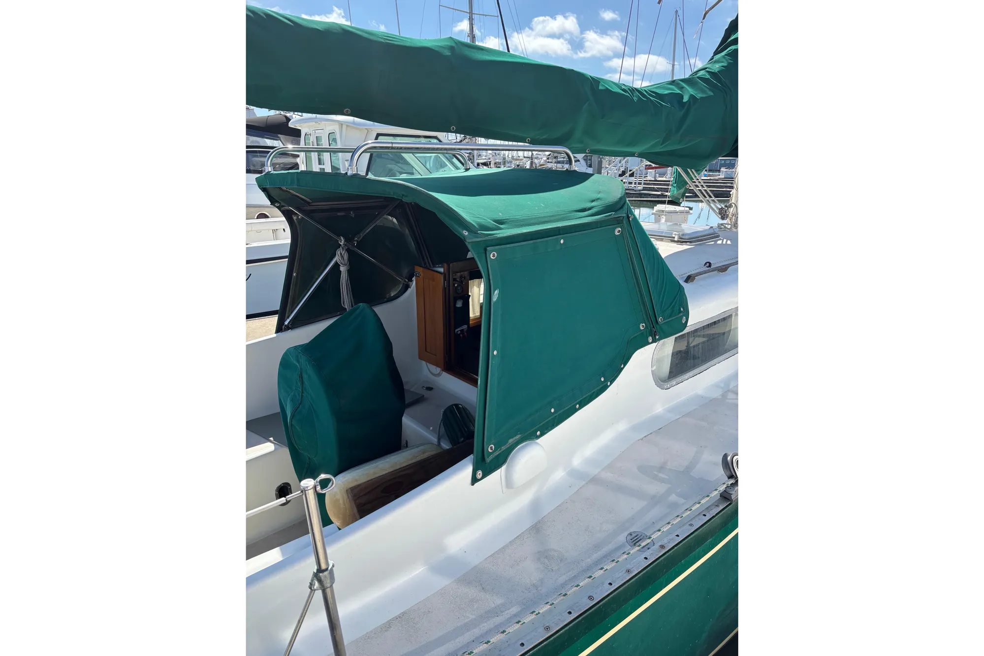 1968 Spencer 35 sailboat with green canvas cover in marina setting.