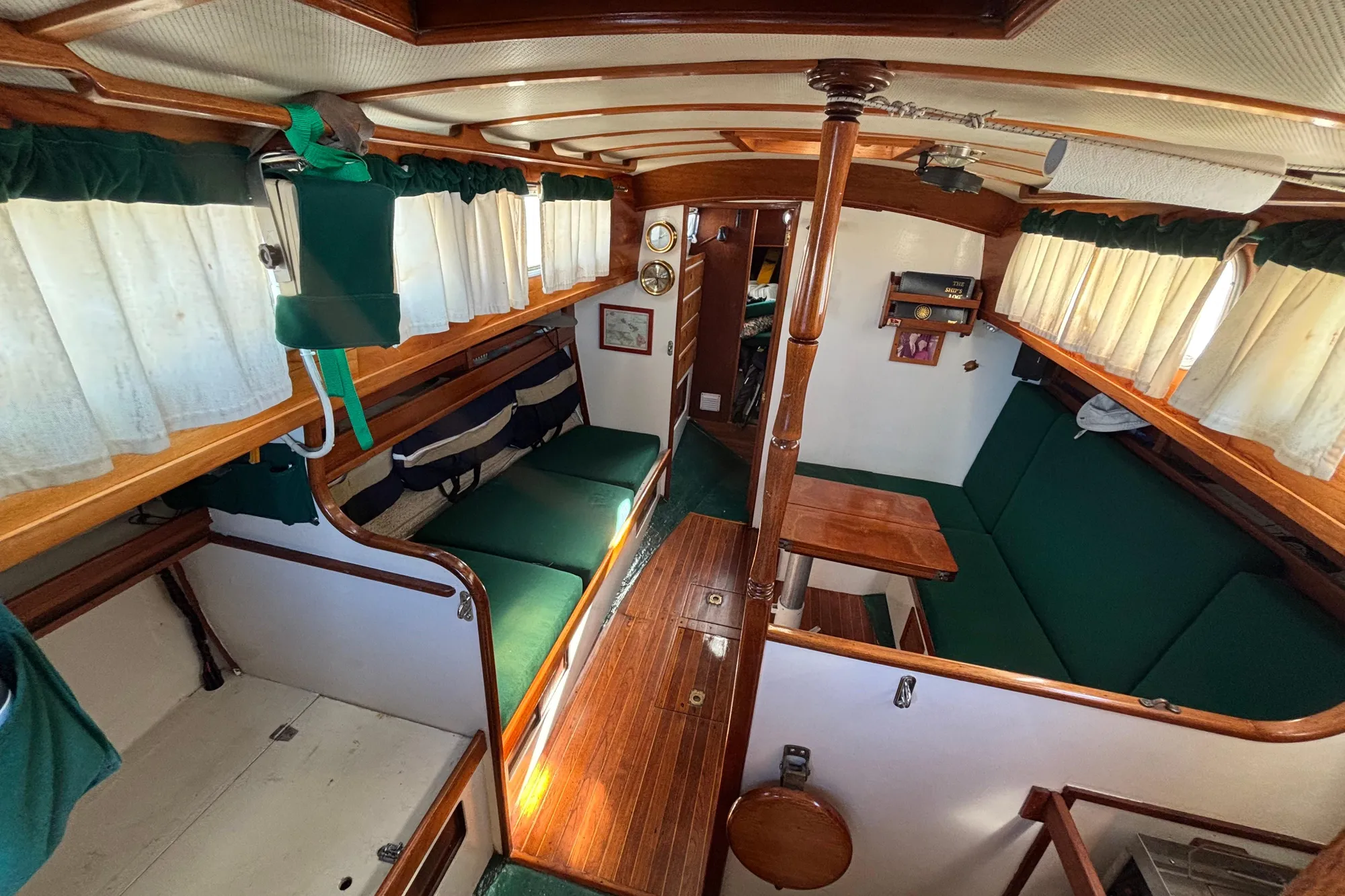 Interior of a 1968 Spencer 35 sailboat with green seating and wooden accents.