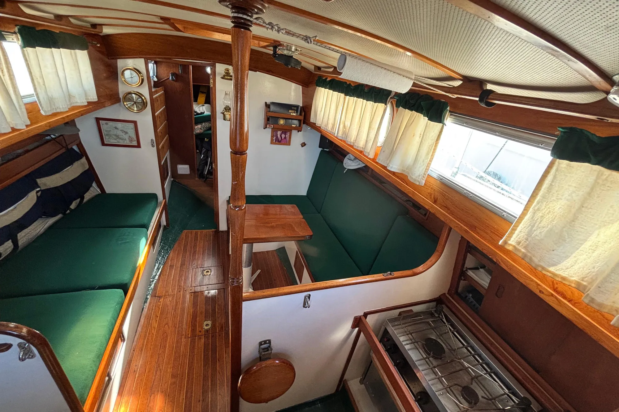 1968 Spencer 35 yacht interior with green seating, wooden accents, and compact kitchen area.