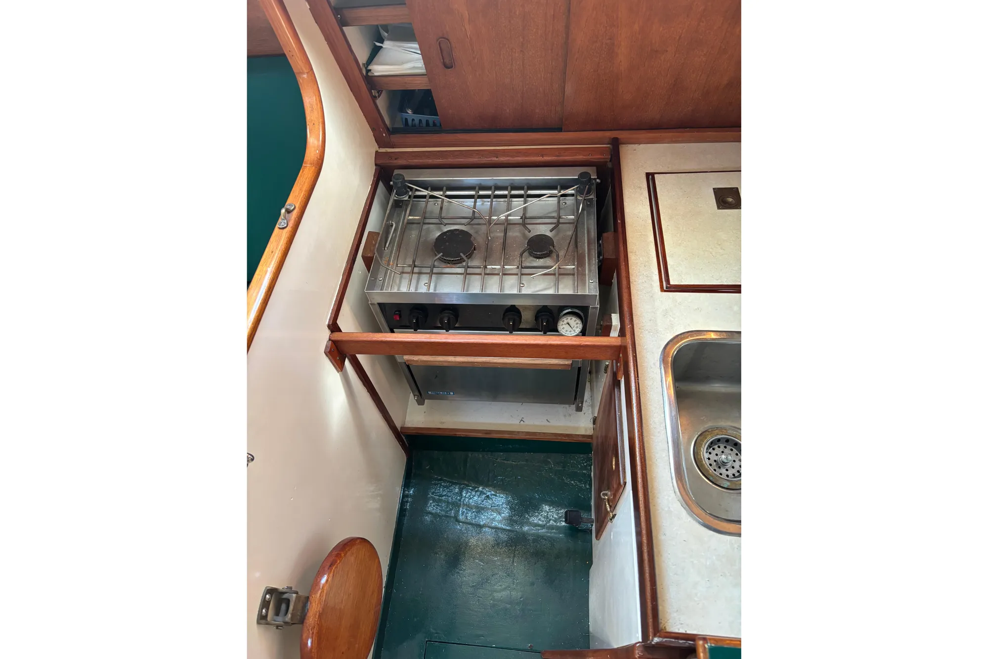 Compact kitchen area in a 1968 Spencer 35 boat, featuring a stove and sink.