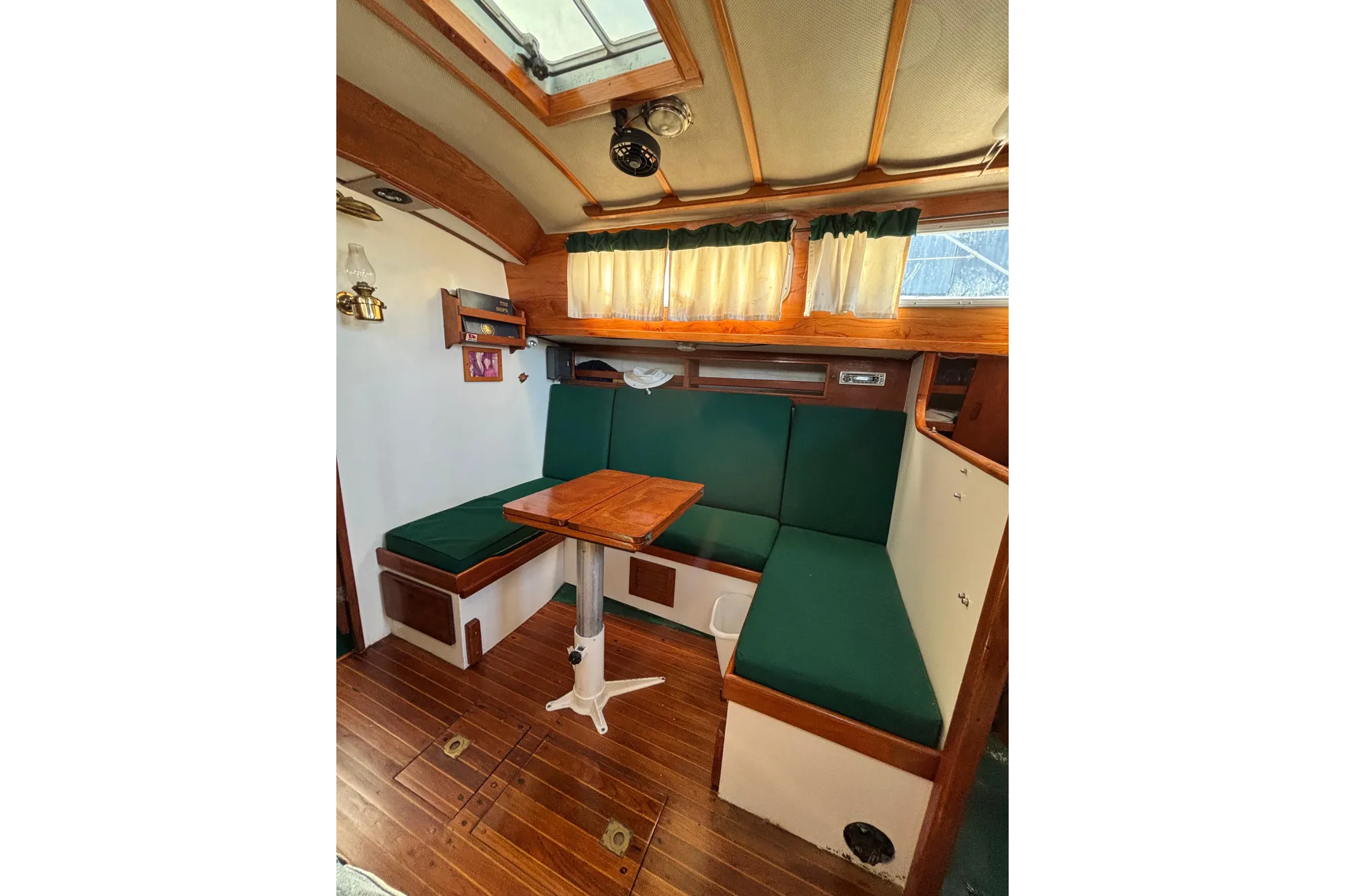 Interior of a 1968 Spencer 35 sailboat with green seating and wooden table.