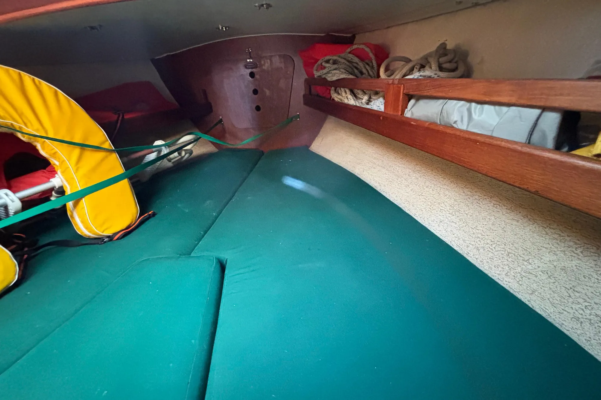 Interior of a 1968 Spencer 35 sailboat with green cushions and storage shelves.