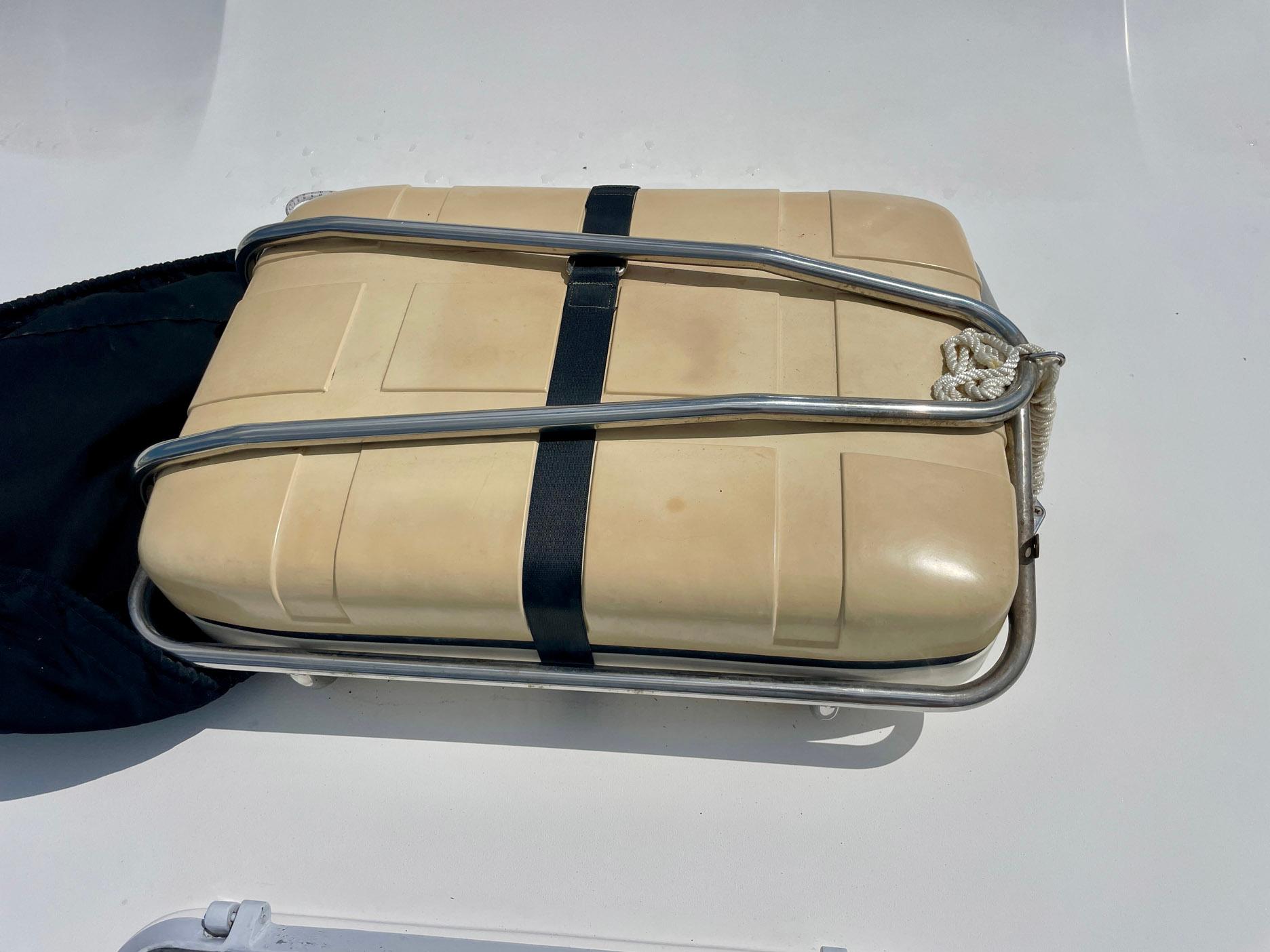 Life raft on 1988 Bertram 43 Convertible boat deck, secured with metal frame and strap.