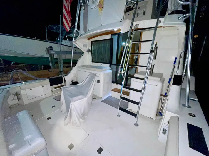 Islander 7 Yacht Photos Pics 1988 Bertram 43 Convertible yacht deck with seating, ladder, and American flag at night.