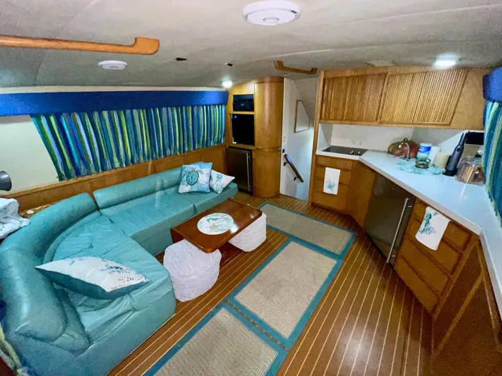 Islander 7 Yacht Photos Pics 1988 Bertram 43 Convertible interior with teal seating, striped curtains, and wooden cabinetry.