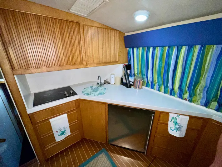 Islander 7 Yacht Photos Pics 1988 Bertram 43 Convertible kitchen with wood cabinets, striped curtains, and modern appliances.
