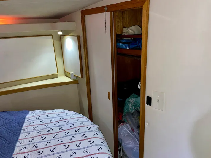 Islander 7 Yacht Photos Pics 1988 Bertram 43 Convertible cabin interior with bed, closet, and nautical-themed bedding.