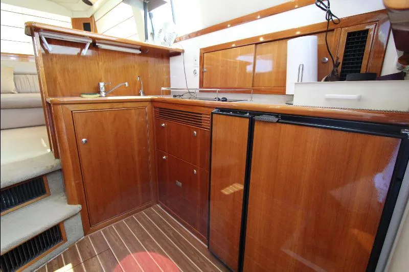  Yacht Photos Pics 2005 Riviera 46 Convertible Sportfisher yacht interior with wooden cabinetry and compact kitchen area.