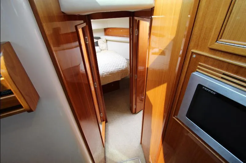  Yacht Photos Pics Interior of 2005 Riviera 46 Convertible Sportfisher, featuring wood paneling and a cozy bedroom.