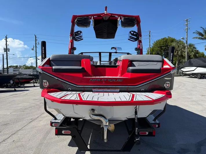  Yacht Photos Pics 2025 Nautique Super Air Nautique G23 boat, red and black, rear view, parked outdoors.