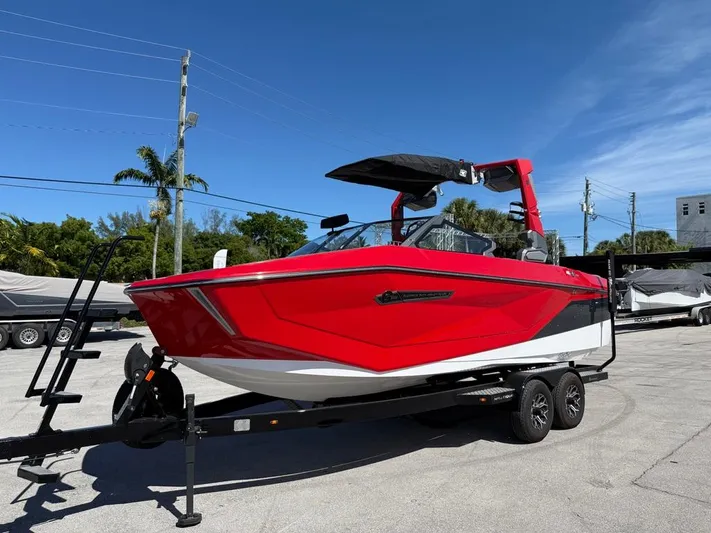  Yacht Photos Pics 2025 Nautique Super Air Nautique G23 boat in vibrant red on a trailer, under clear blue sky.
