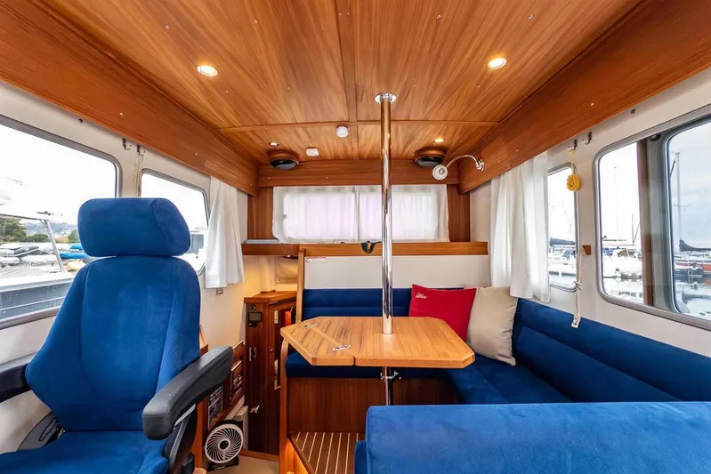  Yacht Photos Pics 2024 Targa 30.1 boat interior with blue seating, wooden table, and windows.