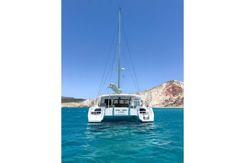 Lasai Yacht Photos Pics 2023 Balance 442 catamaran sailing in clear blue waters near rocky coastline.