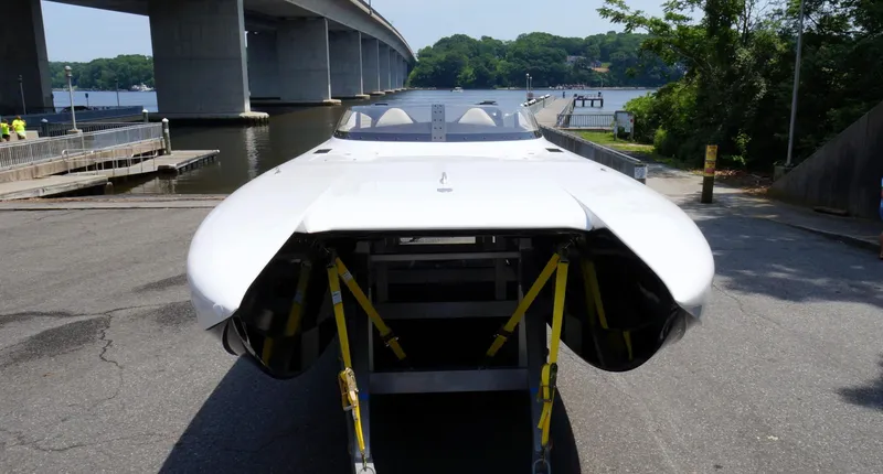  Yacht Photos Pics Doug Wright 32 powerboat on trailer near waterfront, bridge in background, sunny day.