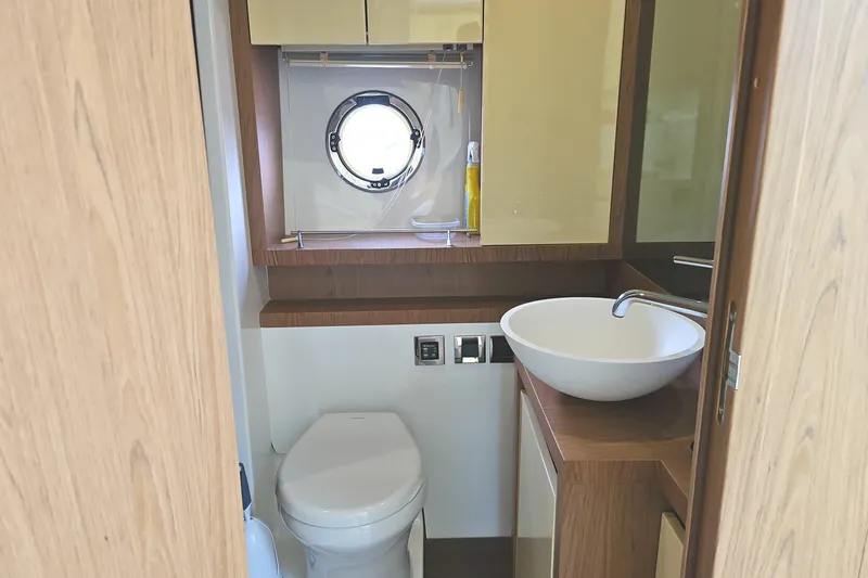 Yacht Photos Pics Bathroom interior of 2015 Beneteau Gran Turismo 49 yacht, featuring modern sink and porthole.