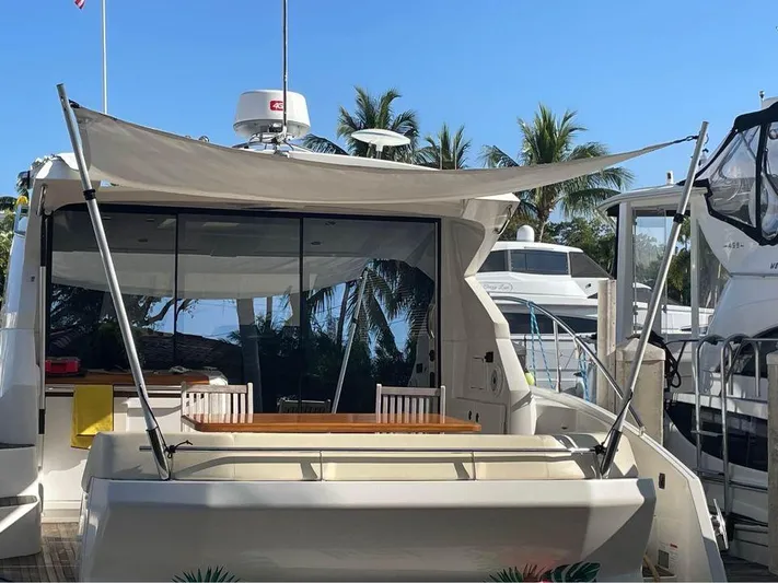 Yacht Photos Pics 2015 Beneteau GRAN TURISMO 49 yacht with canopy, docked near palm trees.