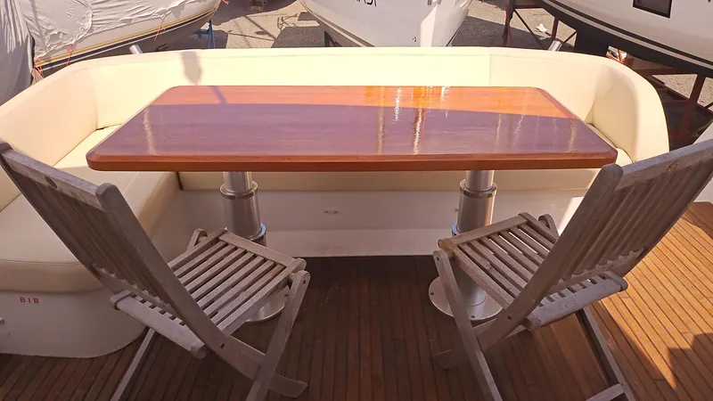  Yacht Photos Pics Outdoor seating area on 2015 Beneteau Gran Turismo 49 yacht with wooden table and chairs.