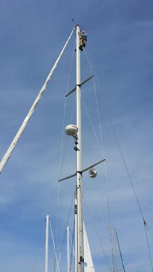Alcyone Yacht Photos Pics Person climbing mast of 2007 Catalina 350 sailboat under clear blue sky.