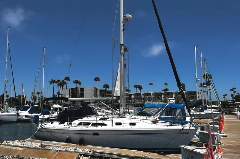 Alcyone Yacht Photos Pics Catalina 350 sailboat docked at marina, clear blue sky, palm trees in background.