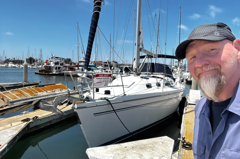 Alcyone Yacht Photos Pics Man smiling beside a 2007 Catalina 350 sailboat for sale at a marina.