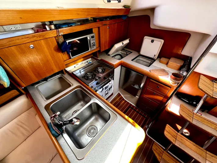 Alcyone Yacht Photos Pics Cozy kitchen in a 2007 Catalina 350 sailboat with wood cabinetry and modern appliances.