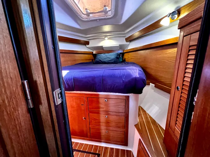 Alcyone Yacht Photos Pics Cozy cabin interior of 2007 Catalina 350 sailboat with wooden furnishings and blue bedding.