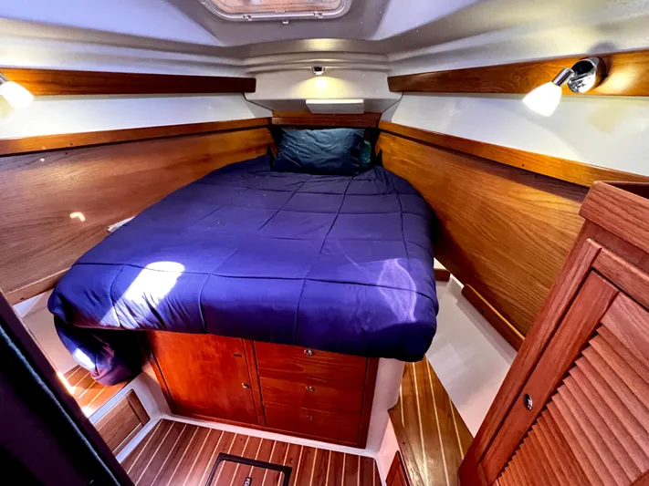 Alcyone Yacht Photos Pics Cozy cabin interior of 2007 Catalina 350 sailboat with wooden finish and blue bedding.