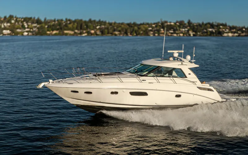  Yacht Photos Pics 2010 Sea Ray Sundancer cruising on a serene lake with scenic background.